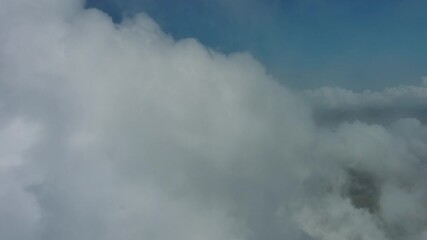 Wall Mural - Flying through beautiful white fluffy clouds in blue sky. Airplane travel background, 4k