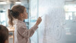 © forenna - enthusiastic teacher explaining the concept of financial freedom to children through a storybook, with illustrations on a whiteboard showing saving, investing, and smart spending.