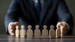 © Almultazam - Wooden Figures in Front of a Businessman's Hands. Business, management, leadership concept.