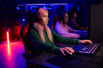 Side view of gamer girl playing pvp fps online game arena in cybercafe.