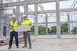 © reewungjunerr - Two Asian engineer working at site of a large building project,Work overtime at construction site,Team of engineer discus at site,The architect, supervisor, and foreman meet to discuss the design
