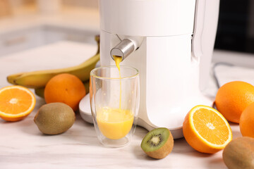 Modern juicer, fresh fruits and glass on white marble table in kitchen, closeup