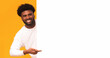 © Prostock-studio - Empty space for advertising. Cheerful african guy pointing at big blank board, orange background, panorama