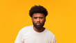© Prostock-studio - Serious afro man posing over orange studio background