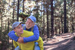 © luciano - Grandson carries his grandfather on shoulders during excursion day in forest. Smiling multi-generational family couple enjoying healthy lifestyle and nature together
