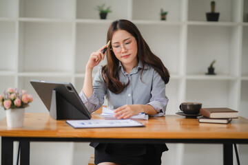 Businesswoman Concentrating: A focused young businesswoman in a modern workspace, absorbed in her work, with a thoughtful expression and a pen thoughtfully held to her temple, conveying a sense of ded