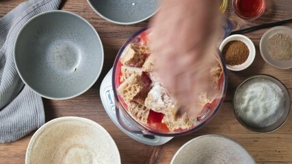 Canvas Print - Process of making gazpacho soup. Cook puts salt and spices in blender with cold tomato soup ingredients, top view