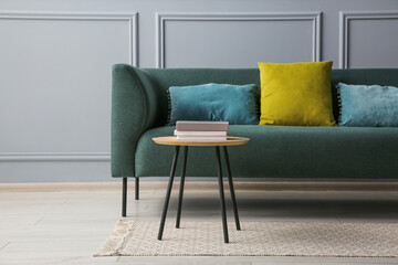 Sticker - Stylish sofa with cushions and books on coffee table in room