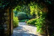 © atar - Stone path leading through a lush green garden with an open doorway and sunlight