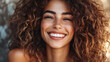© Elnare - A close up of a young woman with curly brown hair smiling.