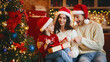 © Prostock-studio - Little festive girl openng xmas gifts on Christmas eve with mom and dad, decorated kitchen interior, copy space