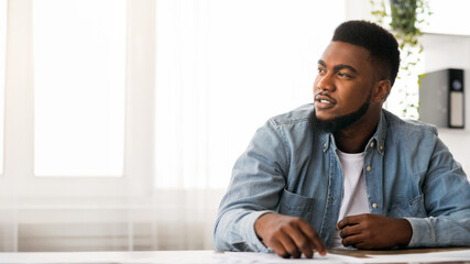 Dreaming about bussiness success. Portrait of thoughtful black businessman at workplace in modern office, copy space