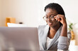 © Prostock-studio - Modern secretary. Smiling black woman in stylish glasses working with papers and laptop at workplace in office, closeup