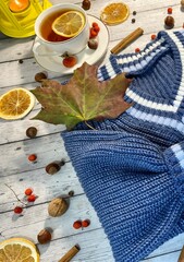 Cozy autumn photo with sweater, cup of tea with lemon and autumn leaves 