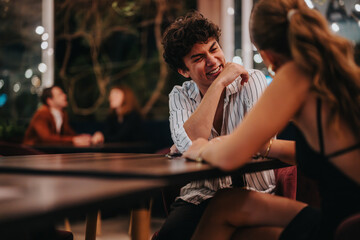 Wall Mural - A young man and woman share laughter and conversation at a charming restaurant setting, creating a lively and engaging atmosphere.