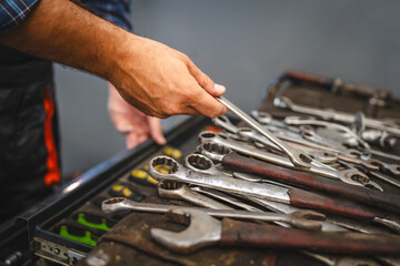 Unknown mechanic organize tools in a toolbox inside a workshop area