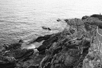 Black and white beach with a huge rock and sea waves. Rock and stone texture