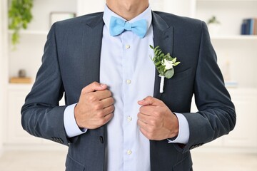 Groom in suit with stylish boutonniere indoors, closeup