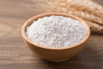 Wheat flour in bowl on wooden table, Food ingredient