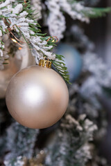 Elegant Christmas tree with white and pink toys in the living room of luxury apartments.Decorative Christmas tree adorned with snow-like frosted branches and a variety of ornamental balls.