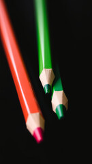 Poster - Closeup of Red and Green Colored Pencils on Black Background