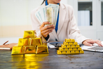 An Asian businesswoman is sitting at her desk, discussing gold bars, deposits,and the gold market with investors.She analyzes gold price trends highlights the long-term benefits of investing in gold