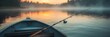 © paisorn - Fishing rod resting on a boat, misty lake backdrop, tranquil scene capturing the essence of a peaceful day by the water