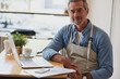 © Sanc/peopleimages.com - Coffee shop, paperwork and portrait of man on laptop for online menu, stock and product inventory. Restaurant, cafeteria and business owner on computer for website, research and planning in store