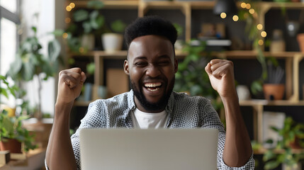 Happy young man in front of laptop computer raising hands and laughing excited about success. Emotional guy feeling glad and euphoric about getting work done and finishing successfu