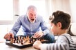 © Halfpoint - Grandpa teaching young boy to play chess. Grandfather spending time with grandson, taking care of him while parents are at work.