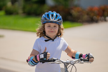 Wall Mural - Child riding bicycle. Little kid boy in helmet on bicycle along bikeway. Happy cute little boy riding bicycle. Child in the protective helmet for bike cycling on bicycle.