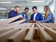 © Westend61 - Carpenters and trainees examining wooden planks in factory