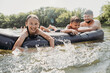 © Westend61 - Smiling man with son and daughter floating on pool raft swimming in river
