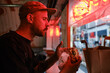 © Westend61 - Man eating sandwich near red neon lighting in restaurant