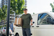 © Westend61 - Delivery person with package holding electric plug and standing near van at street