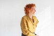 © Westend61 - Smiling redhead woman sitting against white background