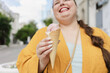 © Westend61 - Cheerful woman holding coned ice cream at street