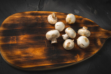 Mushrooms on a wooden cutting board on a dark background. Copyspace.