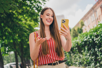 Wall Mural - Photo of adorable cheerful girl wear trendy clothes walk in town speak video call gadget summer time outdoors