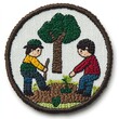 © isti - A circular embroidered patch with two children planting a tree and sapling.