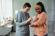 © pressmaster - Nurse checking on newborn while mother holds infant close in hospital room setting Smiling mother engaging with nurse and baby