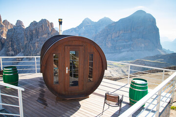 Round outdoor wooden sauna building on the edge of the cliff in the Dolomite mountains.