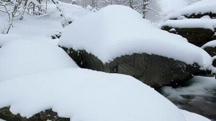 Aufkleber - Snow covers boulders in a peaceful winter forest, creating a serene landscape with a blanket of white