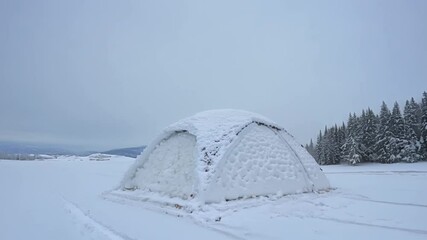 Aufkleber - Thick blanket of snow is covering a small shelter in a wintry landscape, with snow covered pine trees in the background