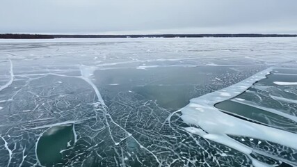 Aufkleber - The frozen lake sparkles in the winter sun, revealing intricate icy patterns in blue and white. Cracks and frost enhance the charm of this breathtaking winter landscape