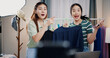 © Johnstocker - Portrait of Two cheerful woman influencers are live streaming to promote a clothing sell during a flash sale on social media or blog in a home studio. Remote shopping, online shopping.