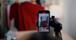 © Johnstocker - Selective focus on mobile phone of Cheerful woman influencer is live streaming sell clothes on social media or blogging in home studio. Remote buying, Online shopping, Sell ​​products online