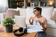 © Srdjan - Young business woman working at home in home office sitting on floor of her apartment, work on laptop computer financial calculations. Female freelance worker using technology for global business.