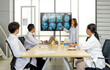 © chadchai - Young asian doctor in white gown  pointing at referencing image of brain scan displayed on a screen during a medical conference. The audience listening attentively with the presentation.