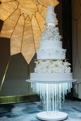 Wall Mural - Luxurious multi-tiered white wedding cake with floral decorations.